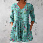 Floral print V neck tunic top shown on a model over slim trousers