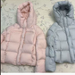 Pastel hooded down puffer jacket laid flat showing the drawcord hood and box quilting