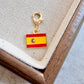 Close view of enamel country flag keychain charms with bright colour and gold clasps