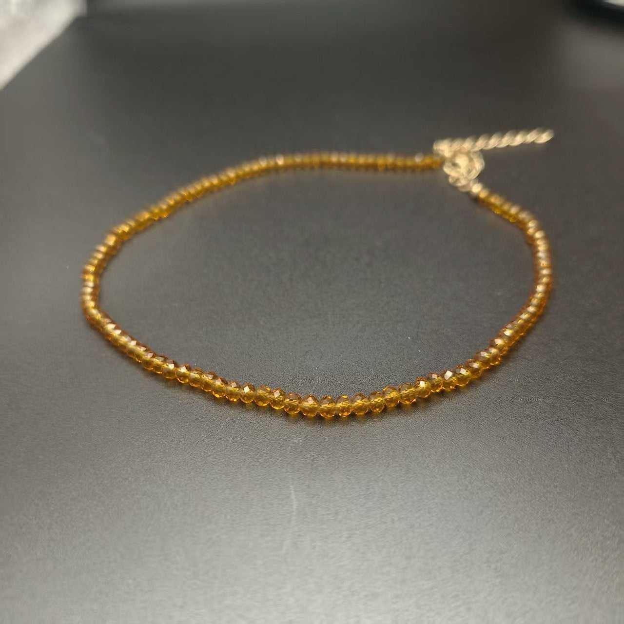 Faceted glass bead necklace coiled to show the choker length and extender