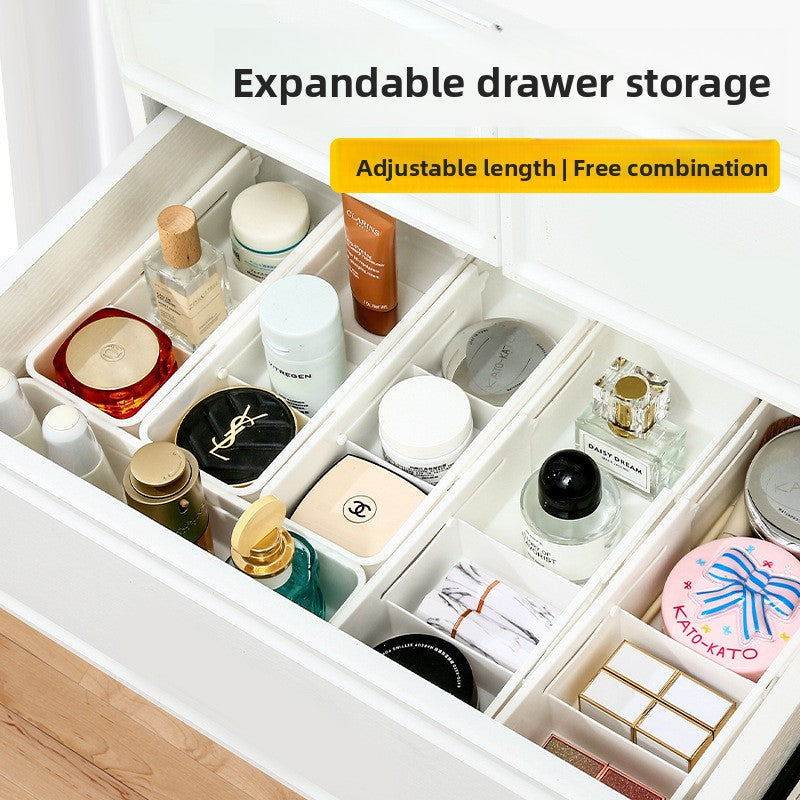 Open drawer neatly divided by several white extendable organizer boxes holding small items