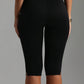 Back view of black high-waisted capri leggings ending below the knee with a small slit at the hem
