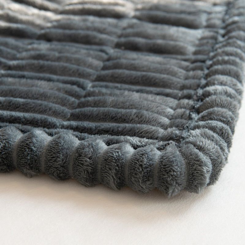 Close-up of a dark gray ribbed plush sofa cover with a rounded scalloped edge