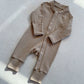 Milk Tea zip front baby romper laid flat on a gray floor, image of the 90 cm, 18 to 24 months size option