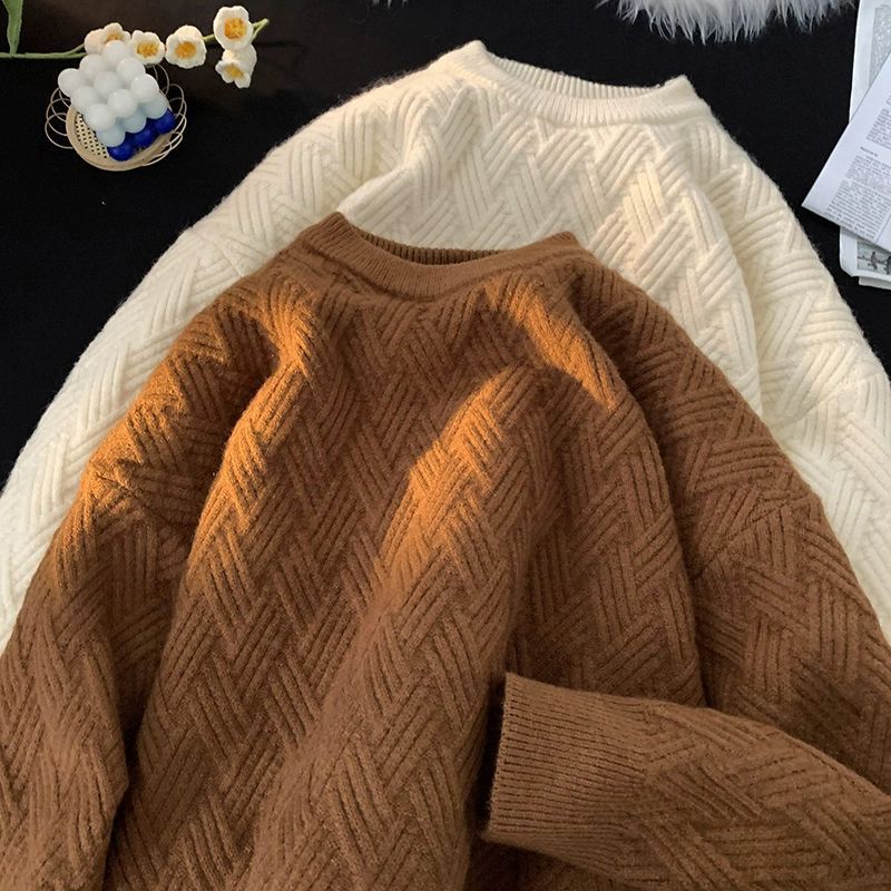 Brown and cream heavyweight knit pullovers laid flat showing the woven jacquard texture