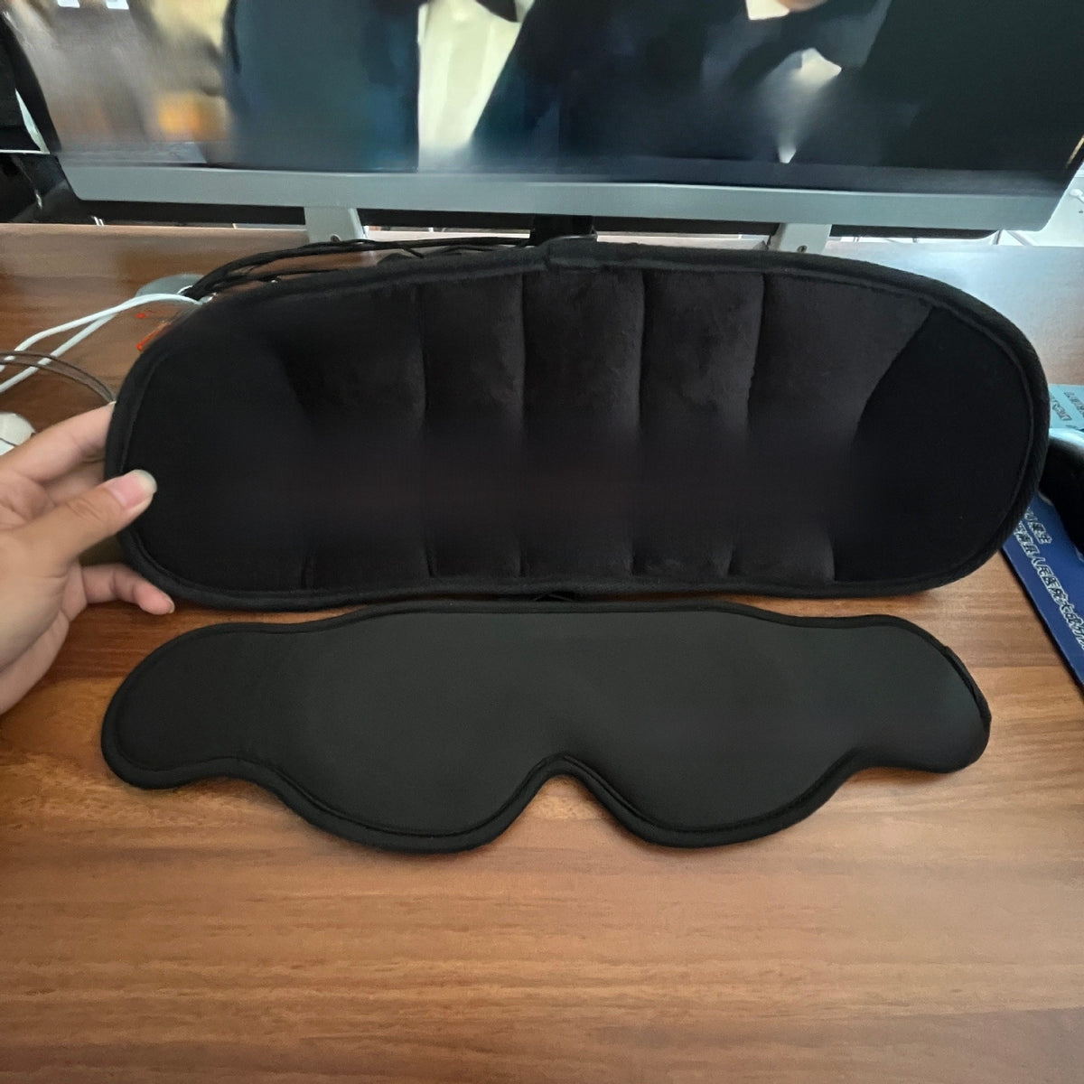 Black zippered pillow with padded channels above a black 3D eye mask on a desk, Pillow New Eye Mask 3D option
