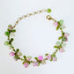 Colorful berry bead bracelet with green enamel leaves photographed on white