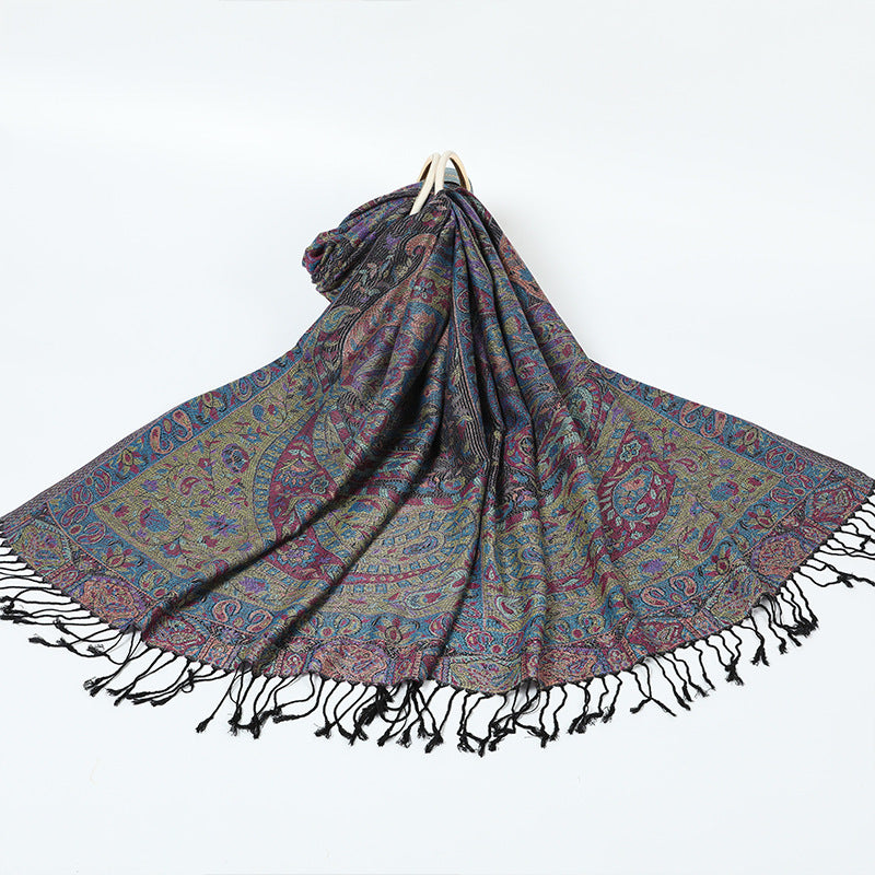 Black paisley shawl with a multicolor border and black tassels spread on a white background