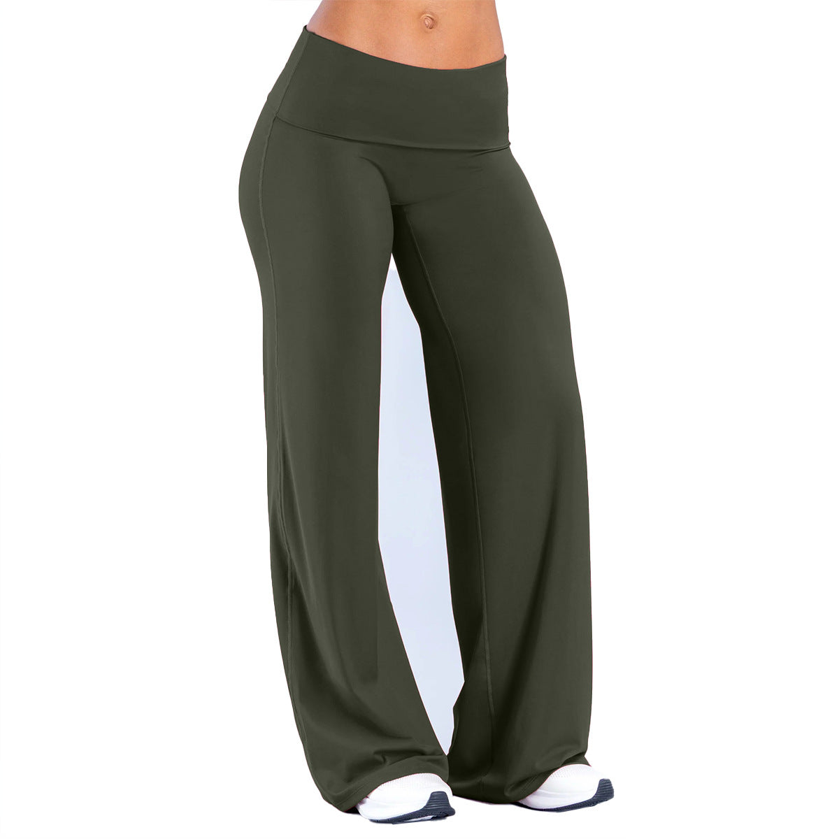Woman in olive green fold over waist wide leg pants and white sneakers on a white studio background