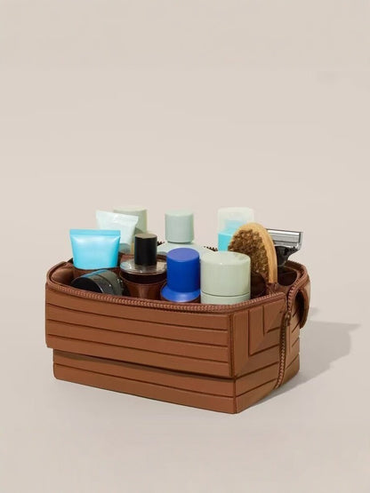 Brown ribbed stripe makeup organizer open and filled with bottles, jars, a brush and a razor