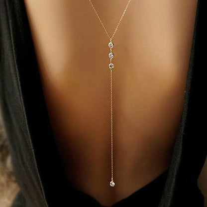 Gold tone rhinestone lariat necklace worn down a models bare back with a low back dress