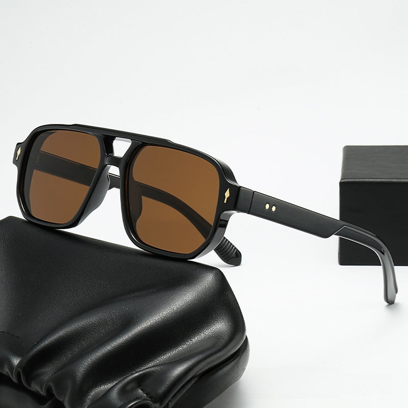 Square double bridge sunglasses with a black frame and brown lenses on a black case