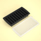 Black nine cavity strip tray beside its cream lid on a pale yellow background, option 9 Cavities Strip Tray, Black