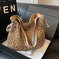 Khaki woven straw shoulder tote with colorful boho strap resting in a gift box