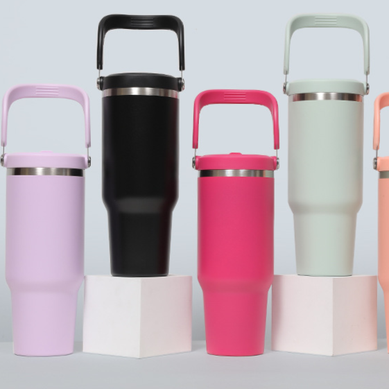 Row of insulated tumblers with handles in lavender, black, hot pink, sage green and coral on white blocks