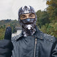 Man in a studded black jacket wearing the gray demon print balaclava and giving a thumbs up