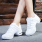 Legs in white lace-up dance sneakers with air cushion heels on a grey carpet