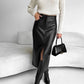 Close view of a black PU leather midi skirt with front pockets, a front slit and black knee high boots