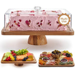 Rectangular acacia cake stand with a clear dome over a pink rose petal cake beside two wooden serving boards