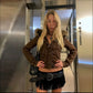 Brown short hooded jacket with a fur trimmed hood worn with a fringe skirt, braided belt and a small star bag
