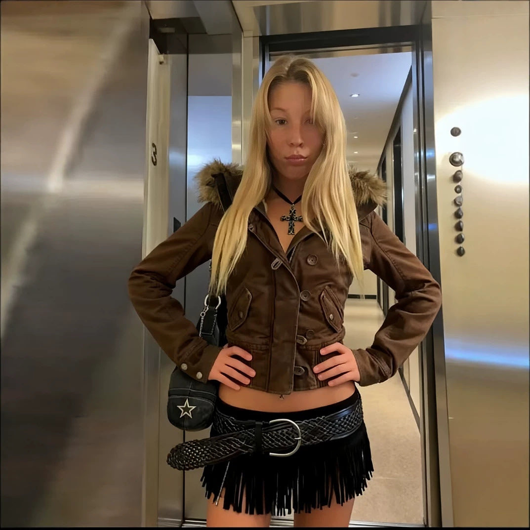 Brown short hooded jacket with a fur trimmed hood worn with a fringe skirt, braided belt and a small star bag