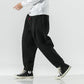 Black plush harem pants in a walking stride, side view showing the loose cut and tapered ankle