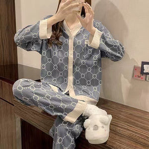 Woman in a slate blue circle print pajama set with cream trim and a chest pocket sitting beside a laptop