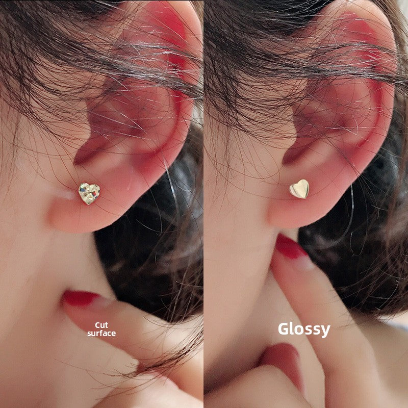 Mini heart gold stud earring at an angle showing the warm gold tone and faceted cut