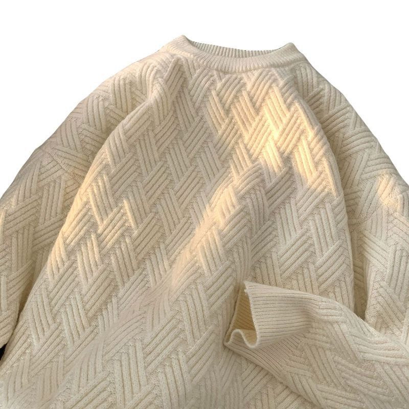 Heavyweight round neck knit pullover with a raised basketweave jacquard texture laid flat