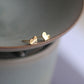 Angled view of the gold-tone wave heart catching light across its surface