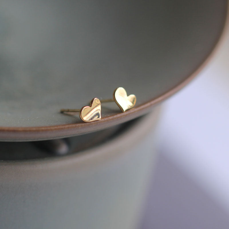 Angled view of the gold-tone wave heart catching light across its surface