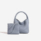 Grey plaited PU bucket bag with soft slumped body and small woven pouch resting against the front