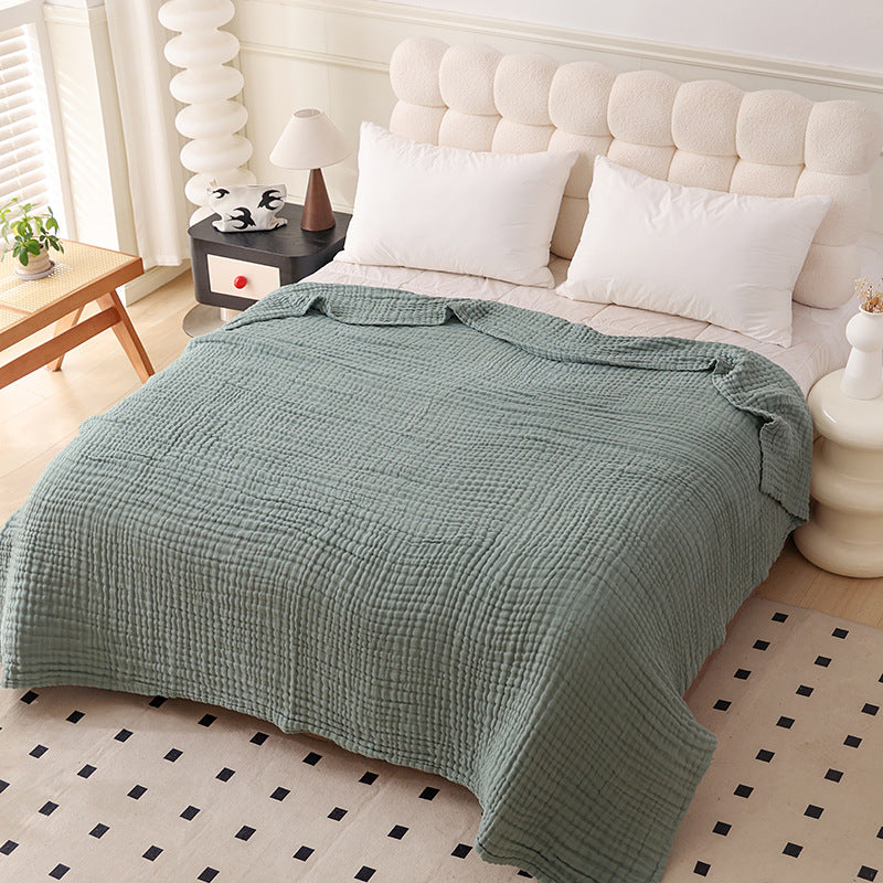 Soft gauze cotton bed blanket draped over a double bed in a muted solid tone