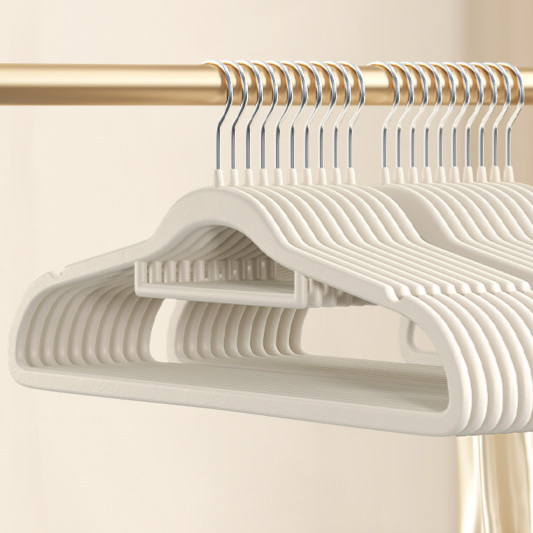 Off-white flocked hangers in a row on a rail, close view of the slim shoulder shape