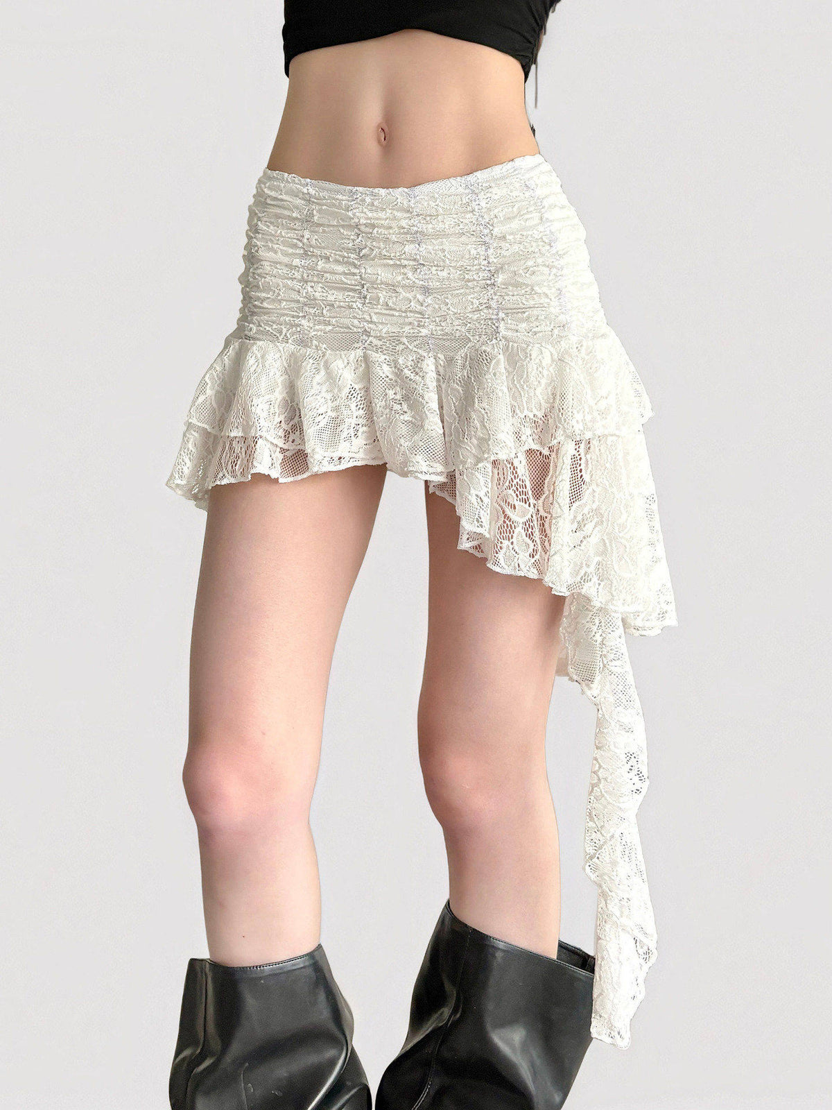 Model in a white floral lace tiered mini skirt with an asymmetric hem and long side tail