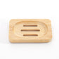 Rectangular bamboo soap dish with an oval shallow well and three drain slots on a white background