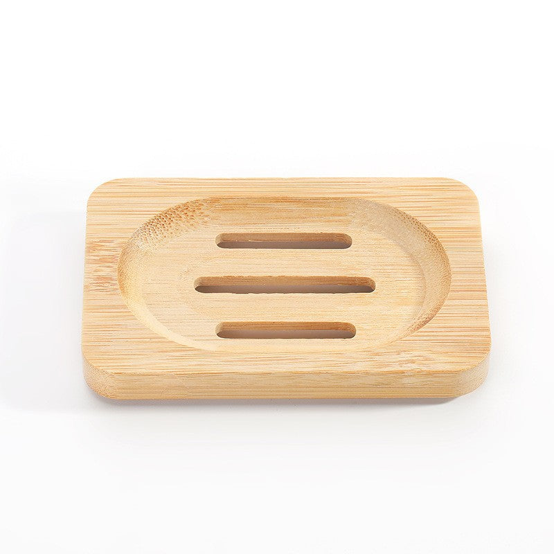 Rectangular bamboo soap dish with an oval shallow well and three drain slots on a white background