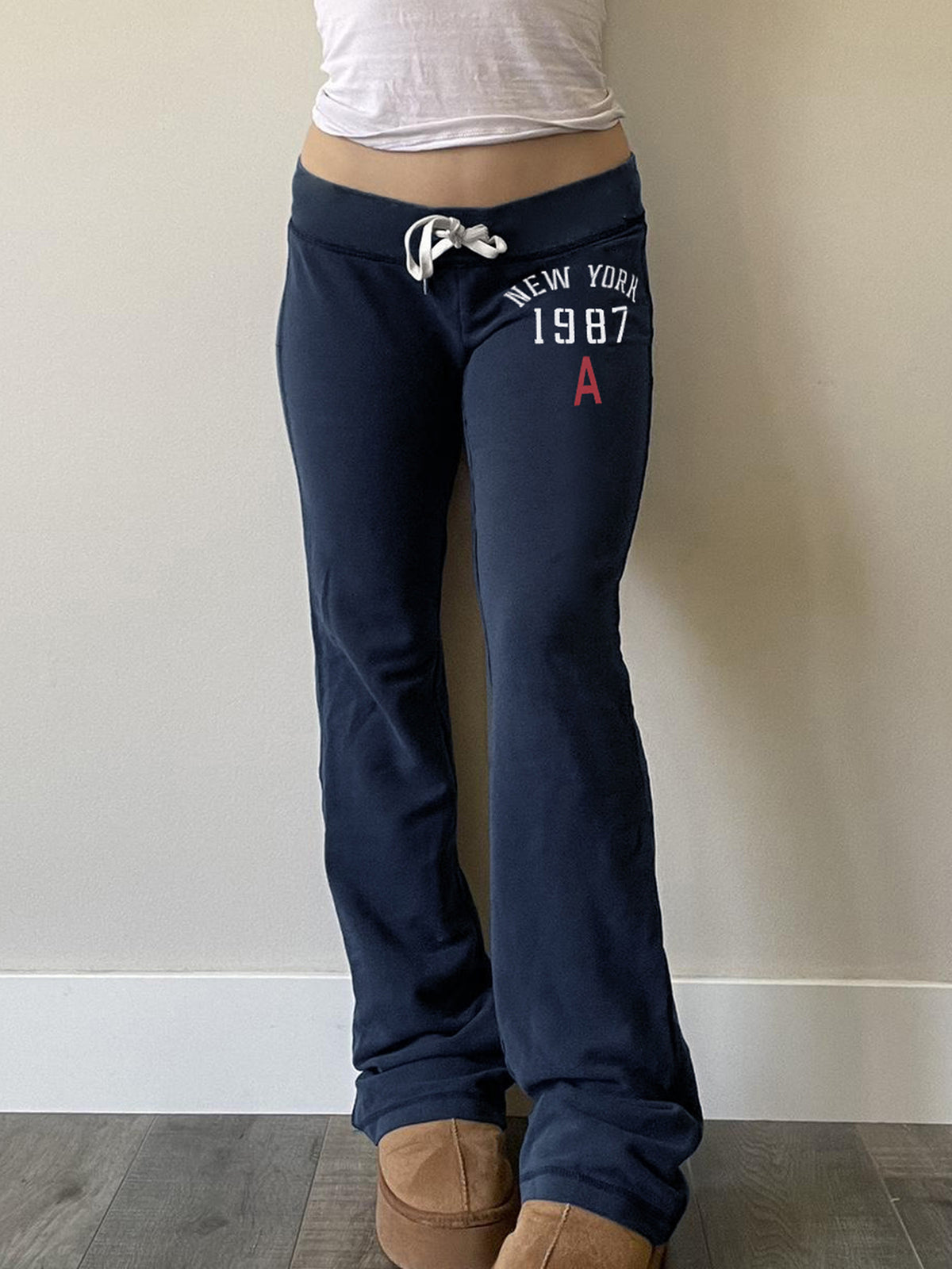 Navy low-rise flared sweatpants with drawstring waist and New York 1987 print worn front
