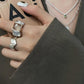 Open silver geometric ring worn on a finger with the accent facing up