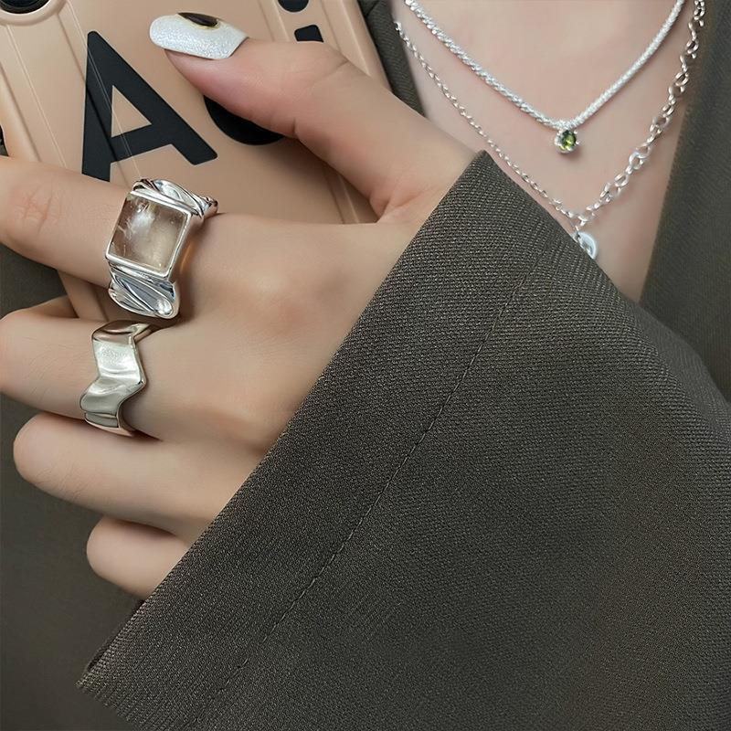 Open silver geometric ring worn on a finger with the accent facing up