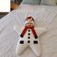 Smiling baby in a white knitted star sleeping bag with a snowman hat on a bed, snowman design not offered