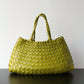 Light green woven handbag with braided handles standing on a dark surface, Light green variant