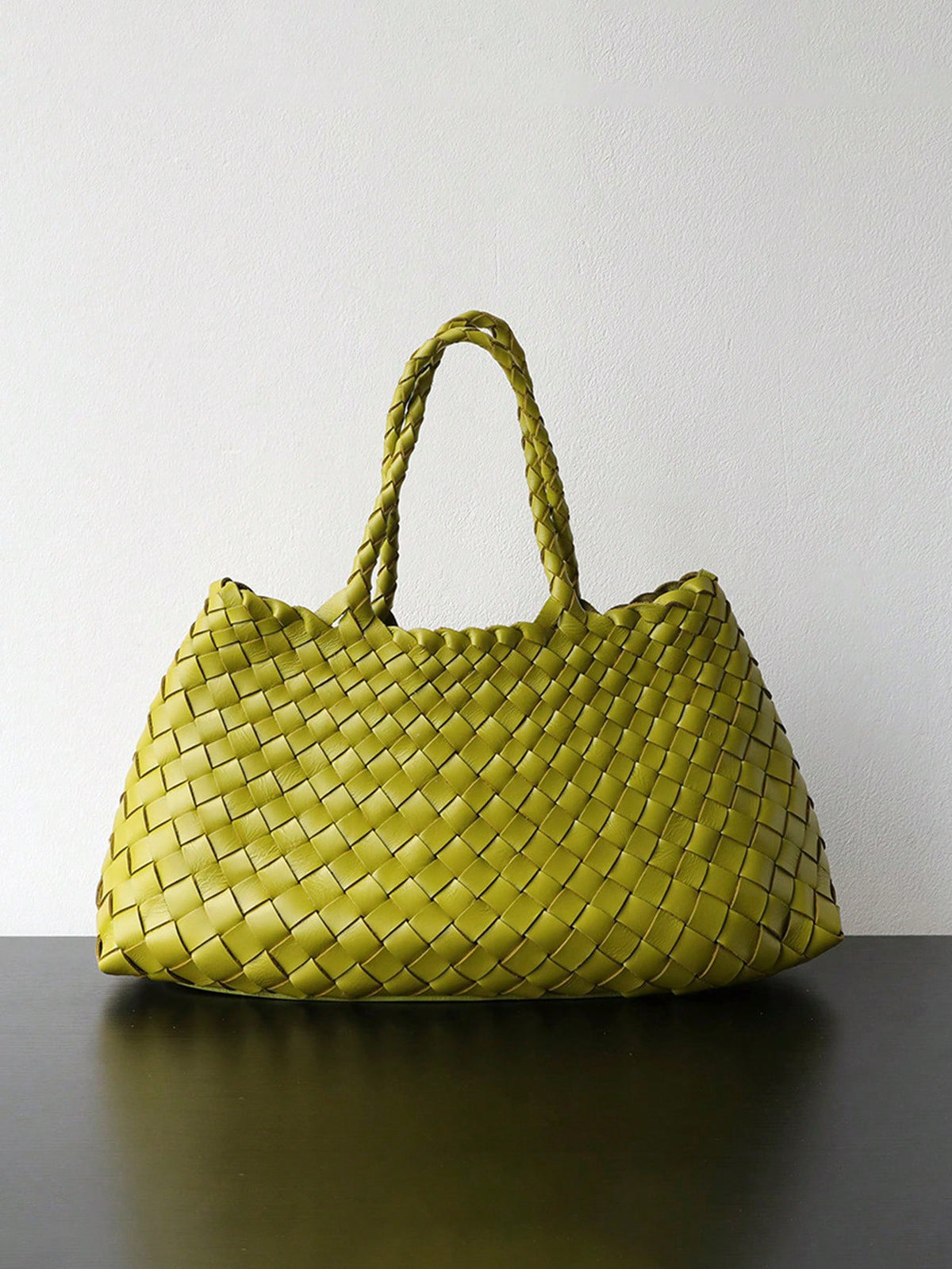 Light green woven handbag with braided handles standing on a dark surface, Light green variant