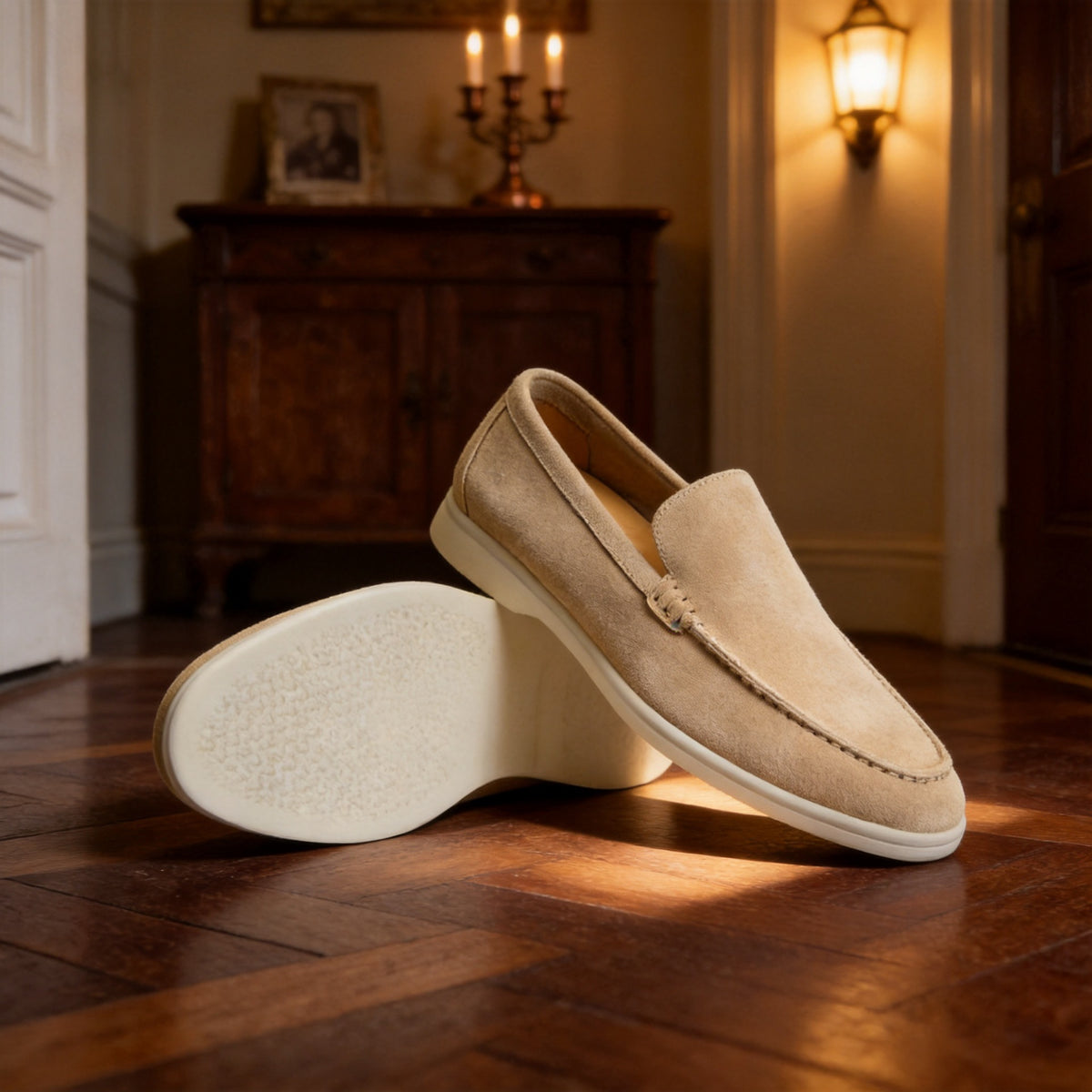 Sand suede slip-on loafer with a thick pale sole next to its sole view, styled on a wooden floor
