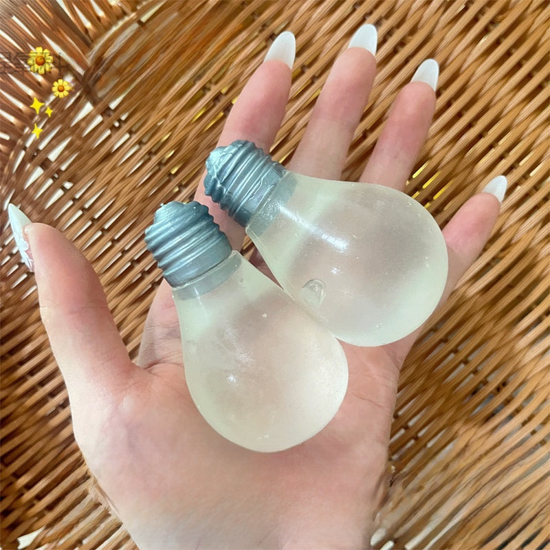 Two milky bulb squeeze toys with moulded grey screw bases resting in a hand over rattan