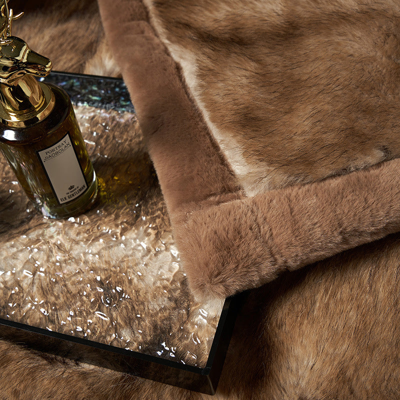 Close-up of the camel fur pile and the smooth brown border at the corner of the blanket, with a perfume bottle