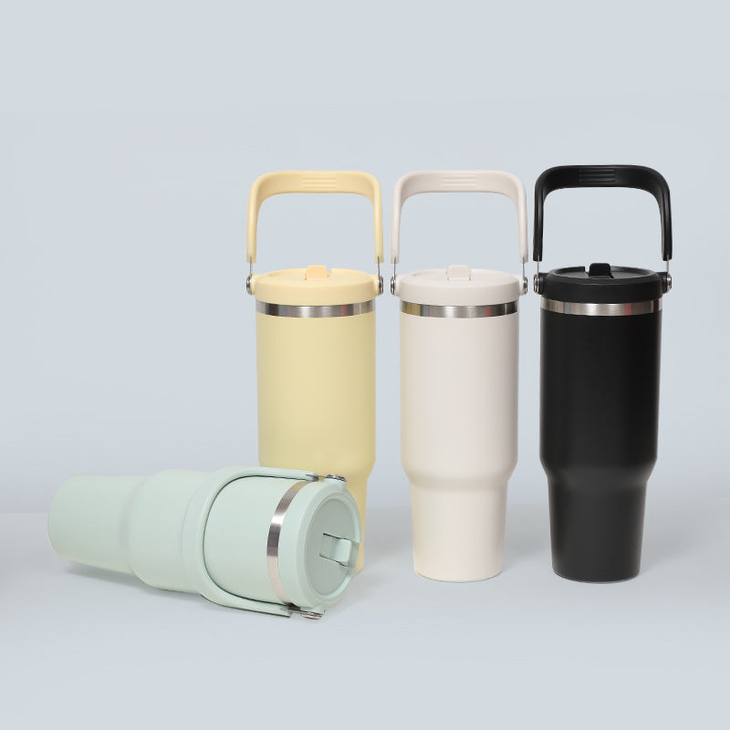 Insulated tumblers with handles in yellow, cream and black, with a sage green tumbler lying on its side
