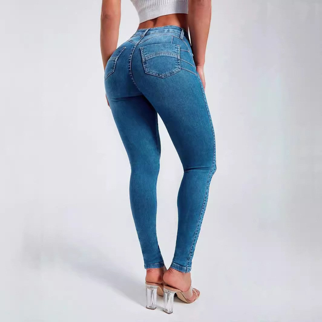 Denim blue skinny jeans back view showing two stitched back pockets, worn with clear block heels
