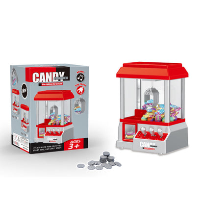 Toy claw machine retail box beside the red and silver machine and a small pile of silver game coins