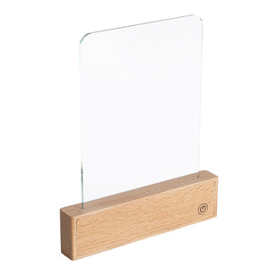 Flat panel LED reading lamp on a beech wood base lighting a magazine on a desk